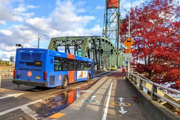 A Trimet bus crosses the Hawthorne Bridge along marked pedestrian and bike paths in downtown Portland