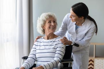 female caregiver or nurse assist take care of smiling senior disabled grandma